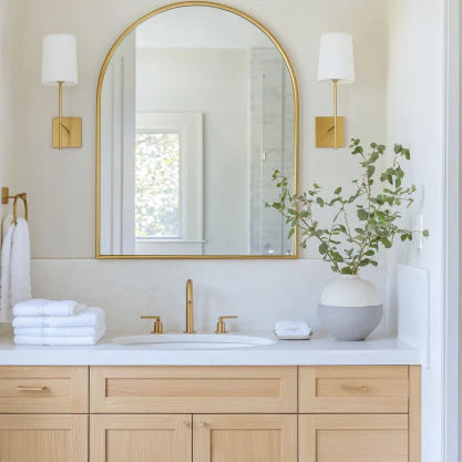 70x55cm Arch Mirror - Aluminum Elegance mounted above a modern bathroom vanity with gold fixtures and light wood cabinetry. Enhances natural light and space.
